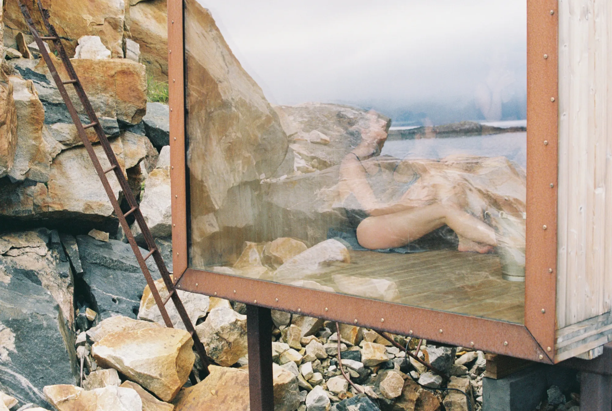A sauna with a big window over a rocky shore