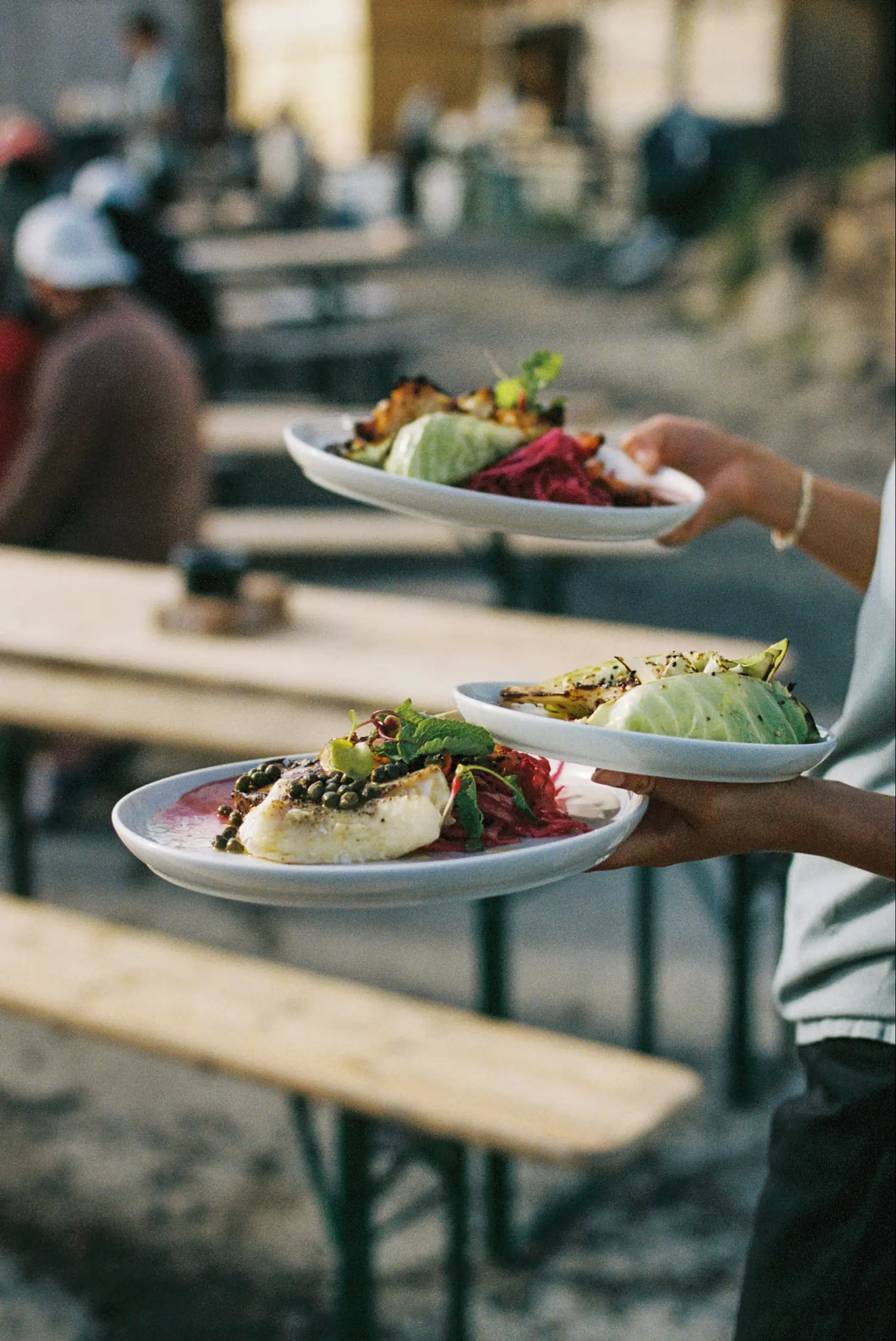 A waiter carrying two plates of food to a table
