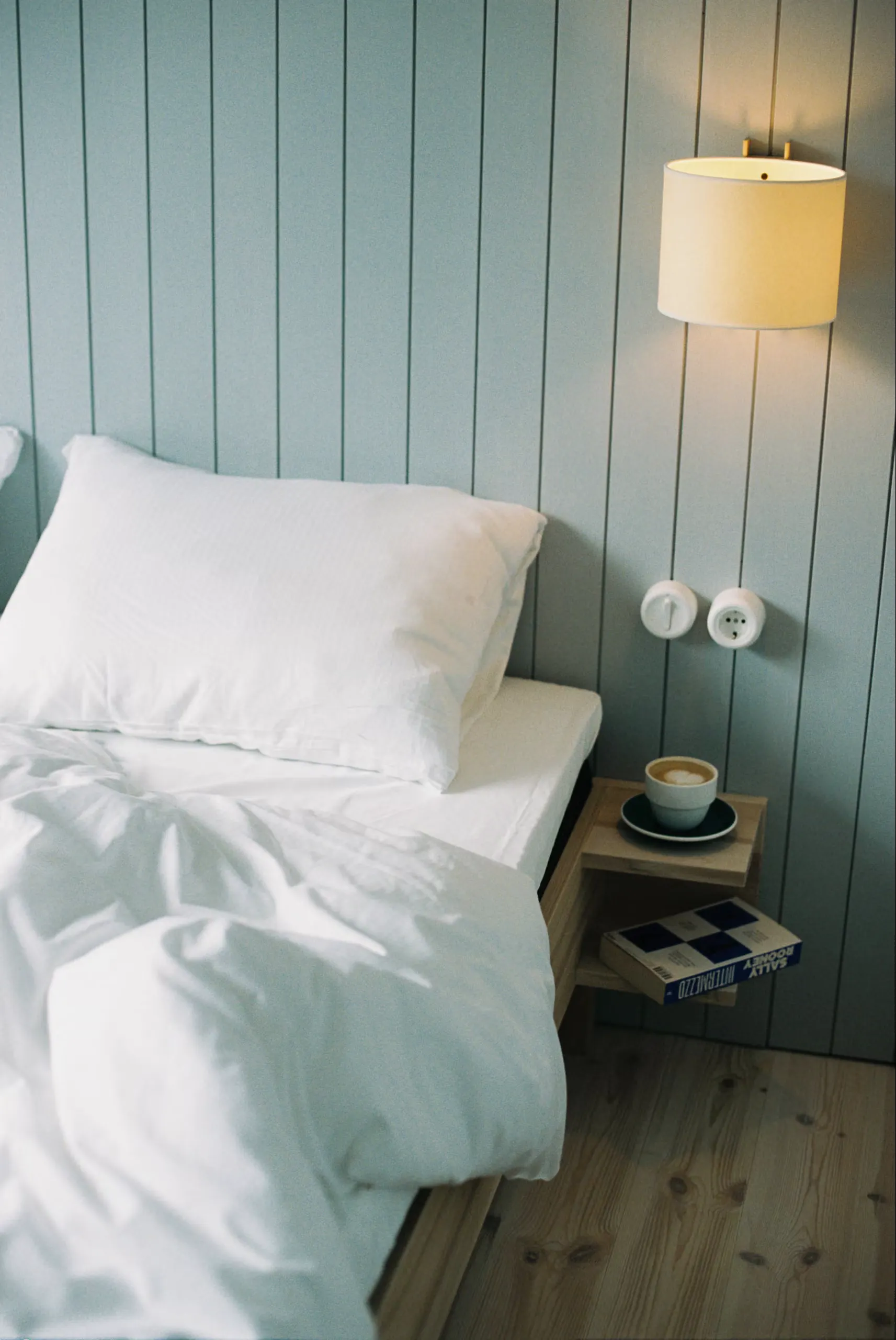 A freshly made bed with white linen and a cup of coffee